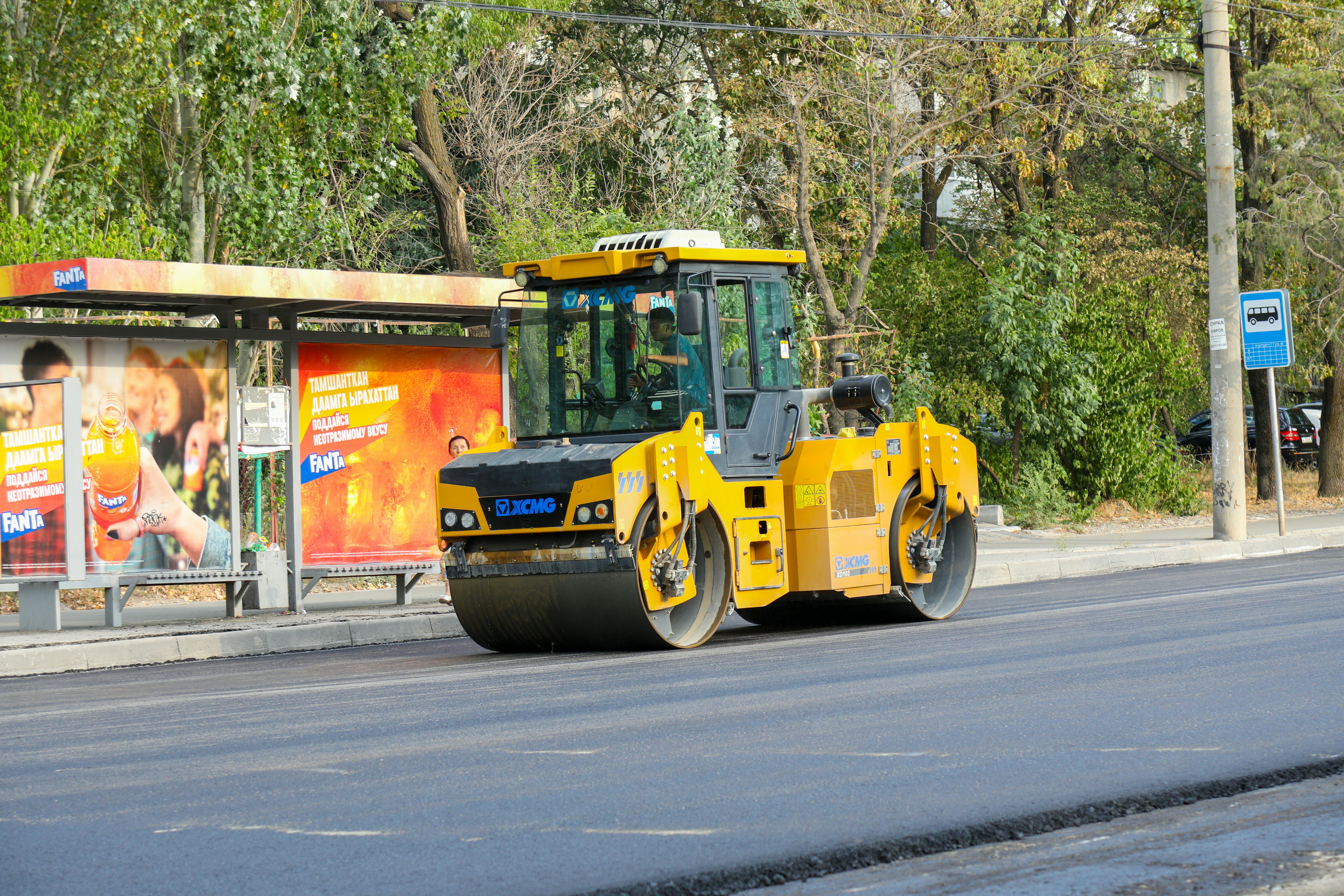 Heavy-duty road roller compacting a freshly paved asphalt surface.